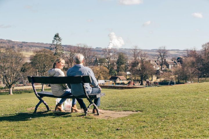 Couple talking about pensions on a bench looking over a park.